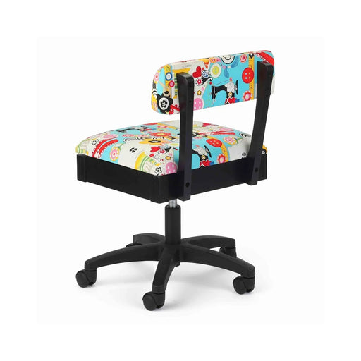 Arrow Sew Wow Hydraulic Sewing Chair – rear angle view showing bright multi-color sewing pattern fabric, sturdy support frame, and smooth-rolling casters.