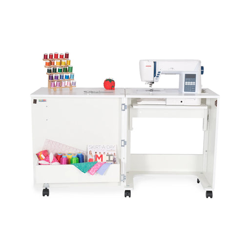 Arrow Judy Sewing Cabinet 101 in White with sewing machine installed, extended workspace, and storage cubby filled with colorful thread and fabric.