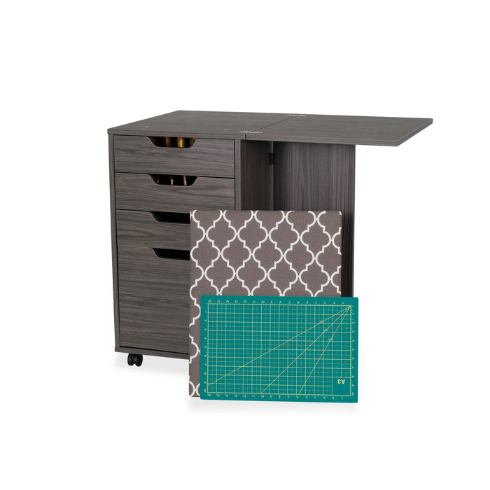 Arrow Sewing Kiwi Storage Cabinet in gray with removable ironing board cover and included cutting mat displayed beside the fold-out workstation.