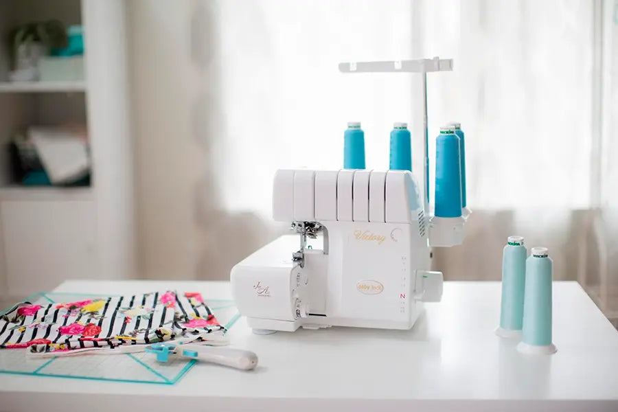 Baby Lock BLS3 Victory Serger set up in sewing studio with fabric and tools, easy-thread serger for home sewing and craft projects.