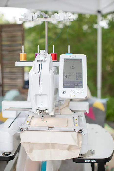Baby Lock Capella embroidery machine threading and hooping setup close-up with touchscreen showing stitch settings.