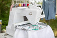 Baby Lock Capella machine embroidering floral welcome design in large hoop with multiple thread colors.