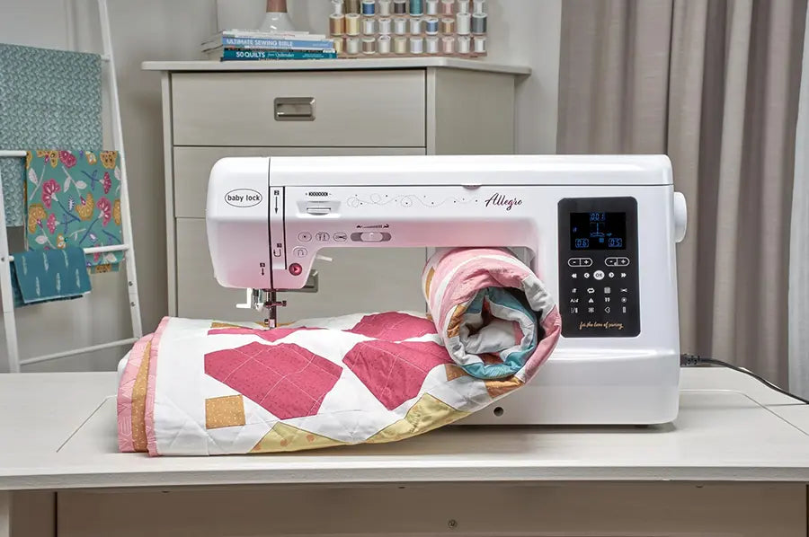 Baby Lock Allegro quilting and sewing machine stitching a rolled quilt in a sewing studio setup