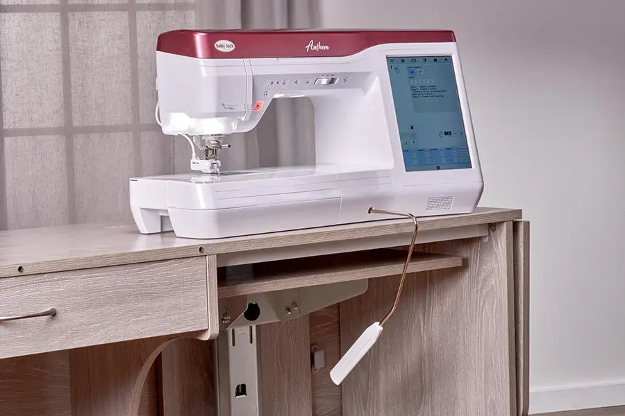 Baby Lock BLAN Anthem sewing machine installed in a sewing cabinet with screen illuminated and needle area lit