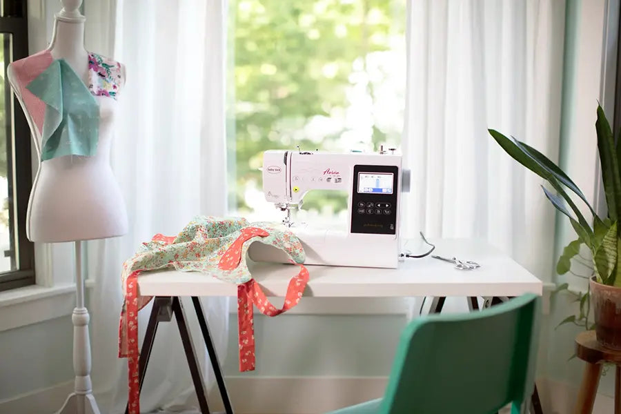 Baby Lock Aurora BLMAR sewing and embroidery machine set up on a crafting table in a bright sewing room.