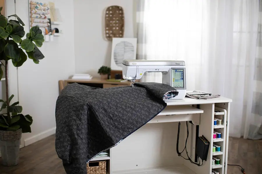 Baby Lock Ballad BLBA sewing and quilting machine stitching a large quilt on a sewing cabinet setup.