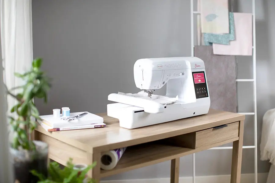 Baby Lock Bloom sewing and embroidery machine displayed on a craft table in a bright home sewing room.