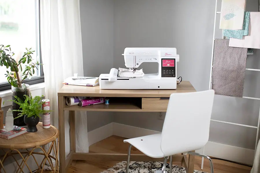 Baby Lock Bloom sewing and embroidery machine setup in a home workspace with natural lighting and sewing supplies.