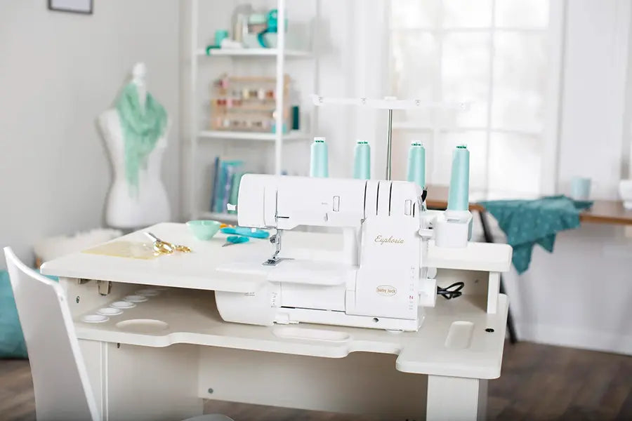 Baby Lock BLC4 Euphoria Cover Stitch Machine set up in sewing studio workspace with thread cones and crafting supplies.