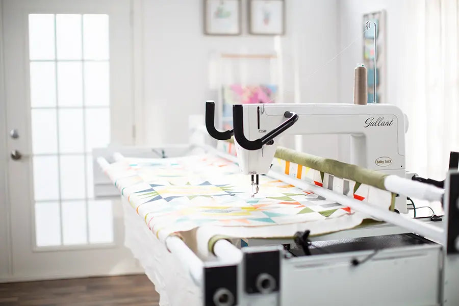 Baby Lock Gallant XL longarm quilting machine stitching a colorful quilt on the Villa 2 frame in a bright sewing studio
