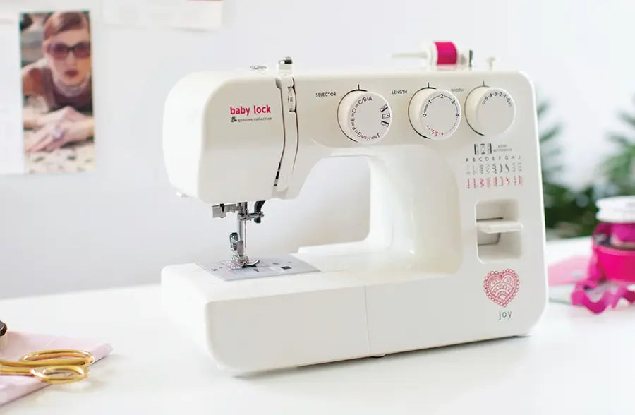 Baby Lock Joy BL25B sewing machine placed on crafting table with accessories, showing lifestyle use in a sewing workspace.