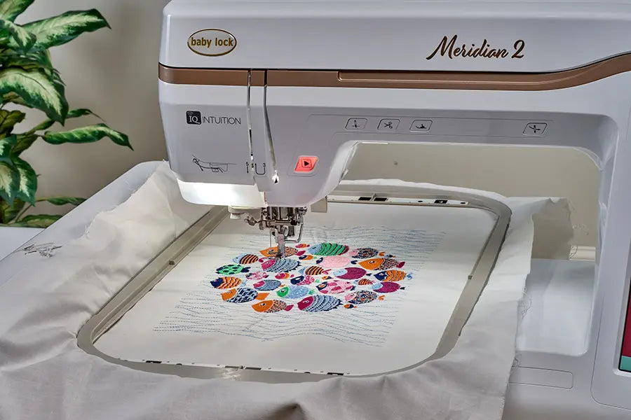 Close-up of Baby Lock Meridian 2 embroidery machine stitching a vibrant multicolor design inside the 9.5 x 14 hoop, highlighting precision Needle Beam placement.