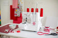 Baby Lock BL460B Vibrant serger machine on a crafting table with sewing supplies—four-thread overlock machine designed for durable seams and decorative finishes.