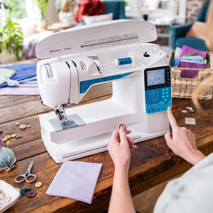 Husqvarna Viking Opal 650 sewing machine in use on wooden table showing user selecting stitches on digital control panel