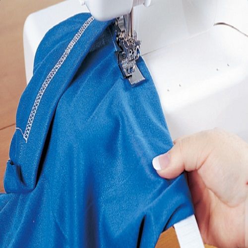 Janome 1000CPX creating a reinforced cover hem on garment fabric, showcasing strong and consistent stitching.