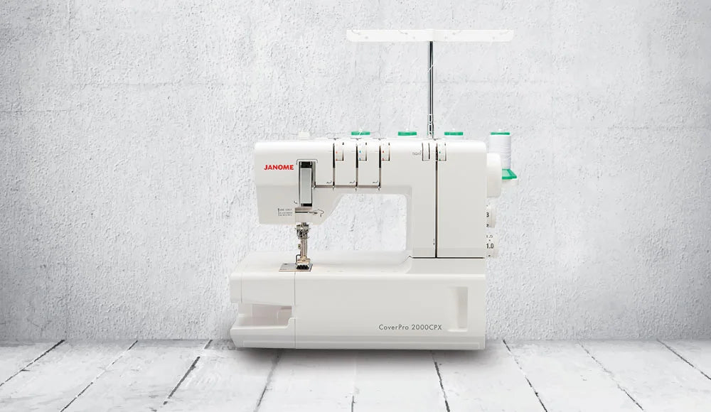 Janome CoverPro 2000CPX coverstitch machine showcased against a studio backdrop, emphasizing its modern design and professional cover hem capabilities.