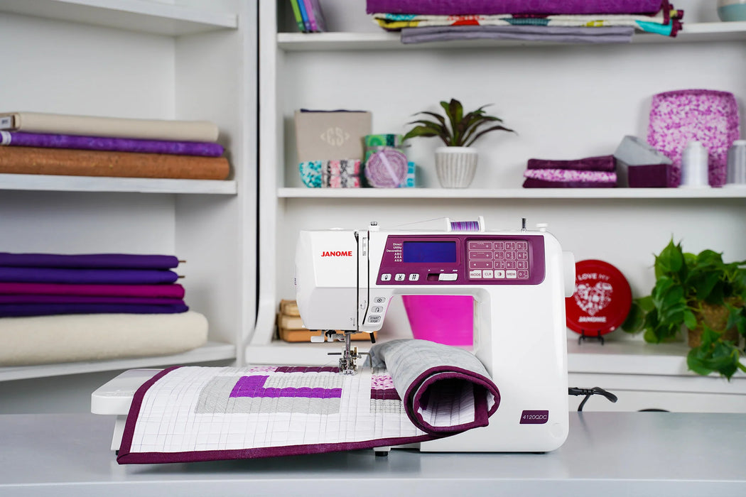 Janome 4120QDC-G computerized sewing machine set up for quilting in a craft studio, demonstrating extended workspace and stitch accuracy.