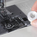 Janome 712T sewing machine drop-in bobbin system with user loading bobbin into transparent bobbin cover for easy threading.