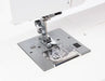 Close-up of Janome Sewist 725S needle plate, presser foot, and drop-in bobbin system for precise stitching.