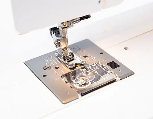 Detailed view of Janome Sewist 725S presser foot and needle plate highlighting feed dogs and easy-access bobbin.