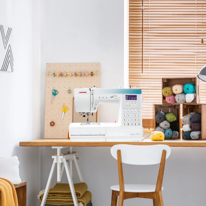 Janome Sewist 780DC computerized sewing machine displayed in a craft room setup with yarn and sewing tools.