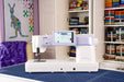 Janome Continental M6 sewing and quilting machine displayed in a home sewing studio with touchscreen active and fabric shelves in background.