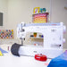 Janome HD9V2 Professional Sewing Machine in a sewing studio setting working on denim fabric with accessories nearby.
