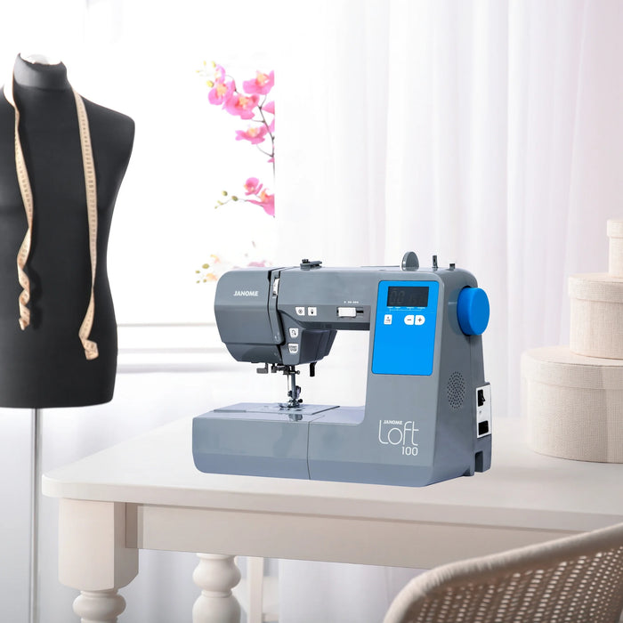 Janome Loft 100 computerized sewing machine displayed on a craft table in a sewing studio setting