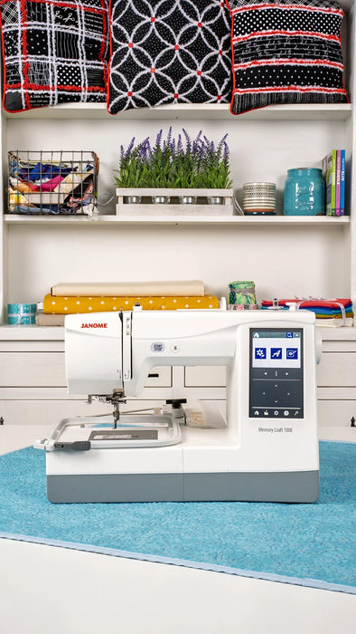 Janome Memory Craft 100E embroidery machine set up in a craft room environment, demonstrating home embroidery capabilities.