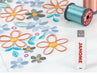 USB drive with exclusive Janome embroidery designs displayed next to finished multicolor floral embroidery sample
