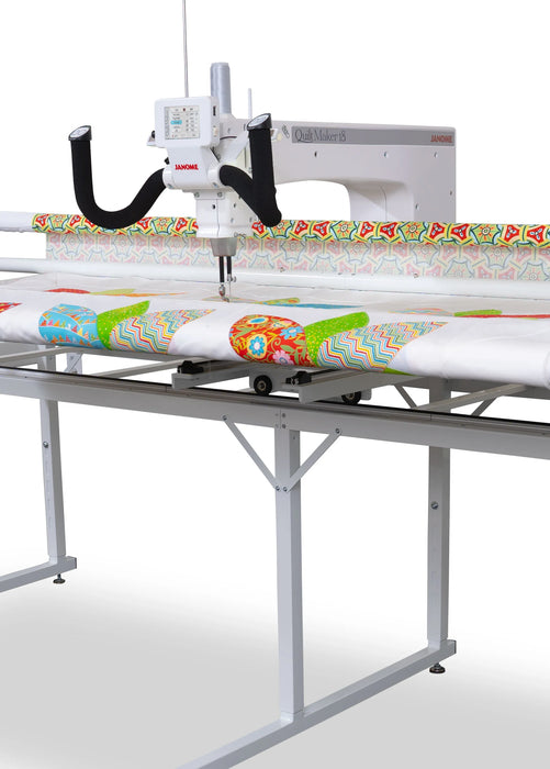 Wide front view of Janome Quilt Maker 15 long arm quilting frame setup holding layered quilt backing and batting
