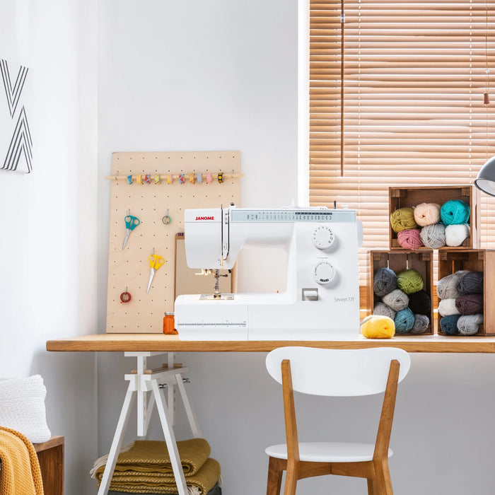 Janome Sewist 721S sewing machine set up in a modern craft room with yarn storage and sewing tools, ideal for hobby and home sewing.