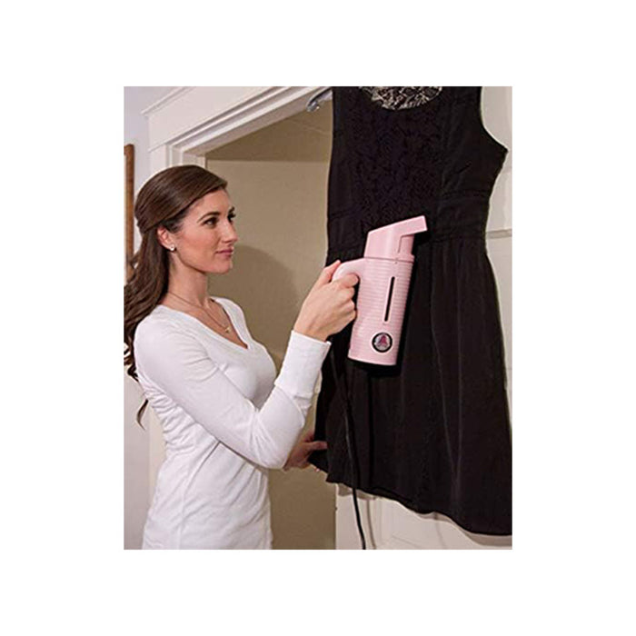 Woman using the Jiffy ESTEAM Pink Travel Steamer to remove wrinkles from a dress, demonstrating handheld garment steaming at home.
