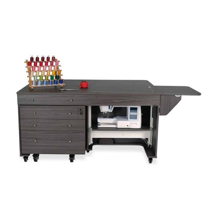 Gray electric lift sewing cabinet with sewing machine lowered inside and storage drawers on wheels