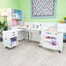 Kangaroo Aussie Sewing Cabinet K8611EL in White set up in a sewing room, featuring electric lift, rolling caddy, and extended quilting surface.