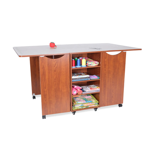 Kangaroo Kookaburra Cutting Table in teak finish with extended work surface and open rear storage shelves filled with sewing supplies.