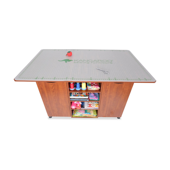 Top view of the Kangaroo Kookaburra Cutting Table with cutting mat placed on the full work surface and visible rear storage shelving.