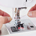 Close-up of SINGER Elite CE677 sewing machine needle area demonstrating automatic needle threader and drop-in bobbin system in use